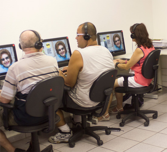 Foto de um curso realizado na Fundação Dorina, há três alunos sentando na frente de computadores.