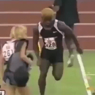 Descrição da imagem: Moça caminha  por uma pista de atletismo e é atropelada por um atleta que corre em alta velocidade. Fim da descrição.