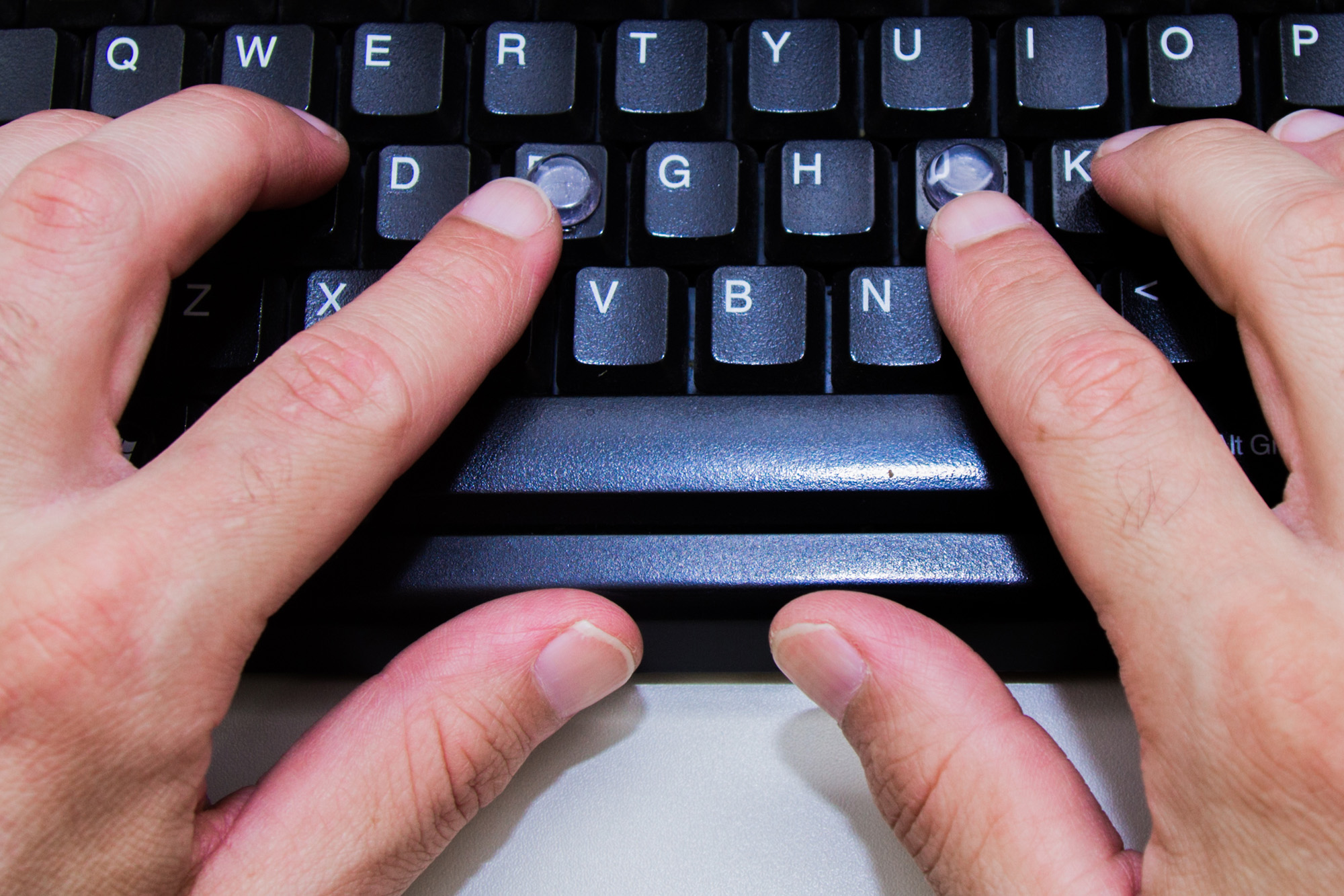 Foto de duas mãos sobre um teclado.