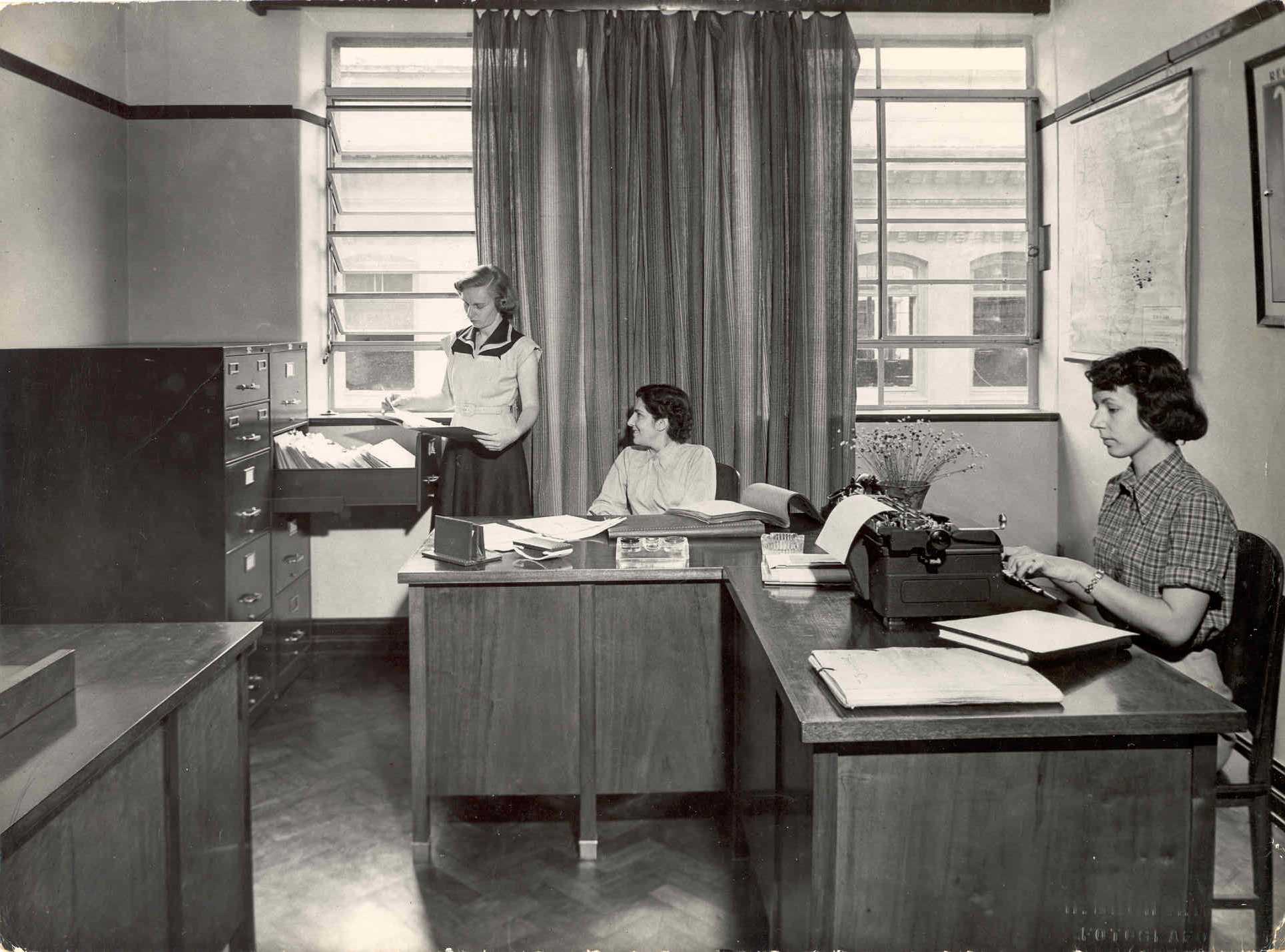 Imagem preto e branco. Três mulheres trabalhando na primeira sede da Fundação.
