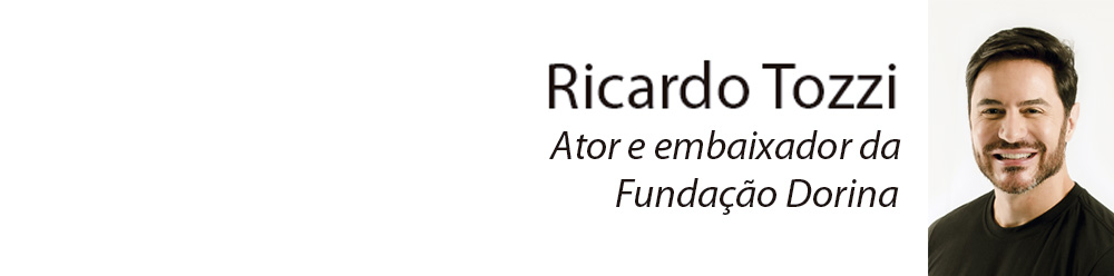 Descrição da imagem: retrato de Ricardo Tozzi do peito pra cima. Ele tem pele clara, cabelos castanhos, curtos e lisos, barba curta, usa camiseta preta, olha pra frente e sorri.