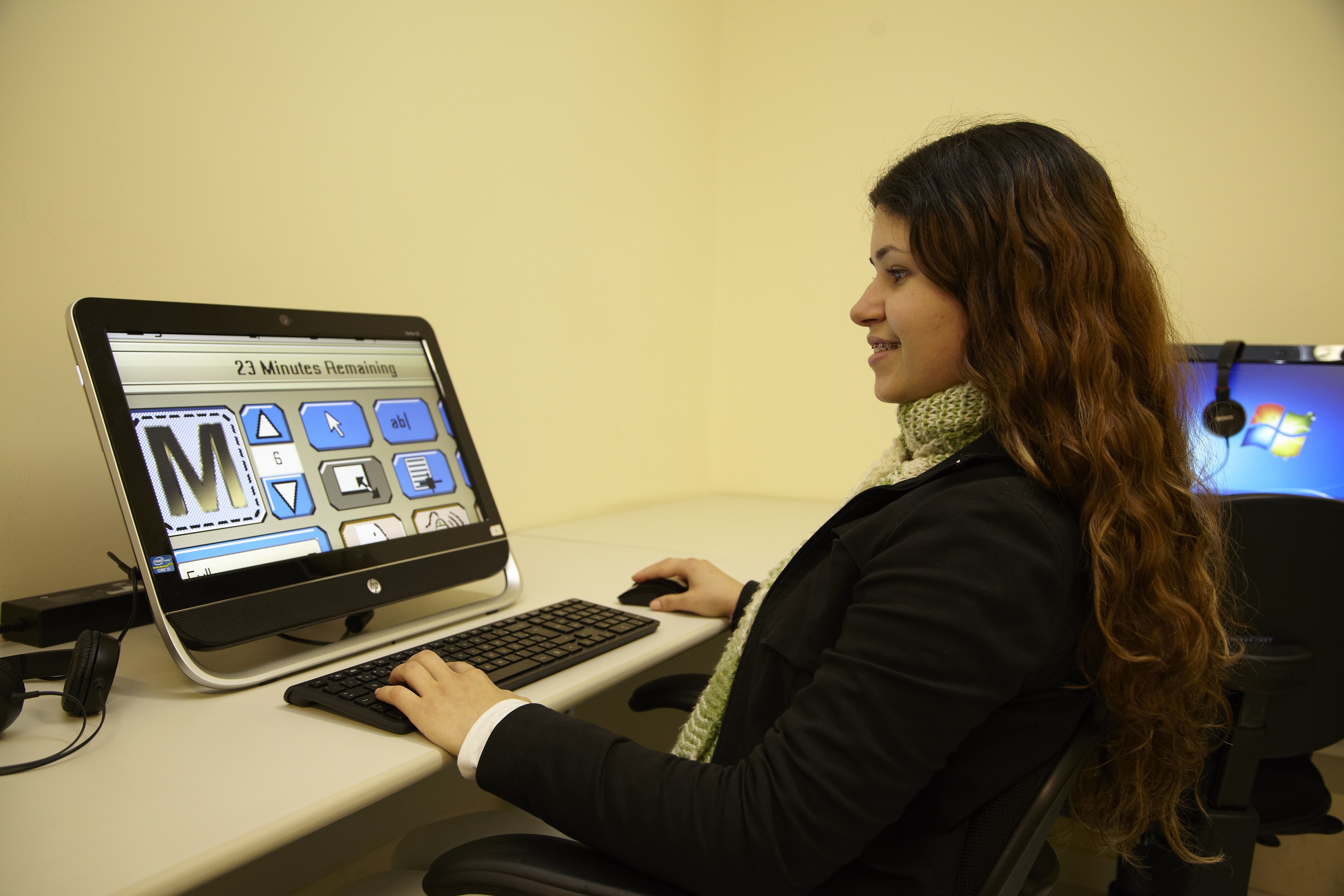Descrição da imagem: foto de mulher sorridente de perfil usando computador.
